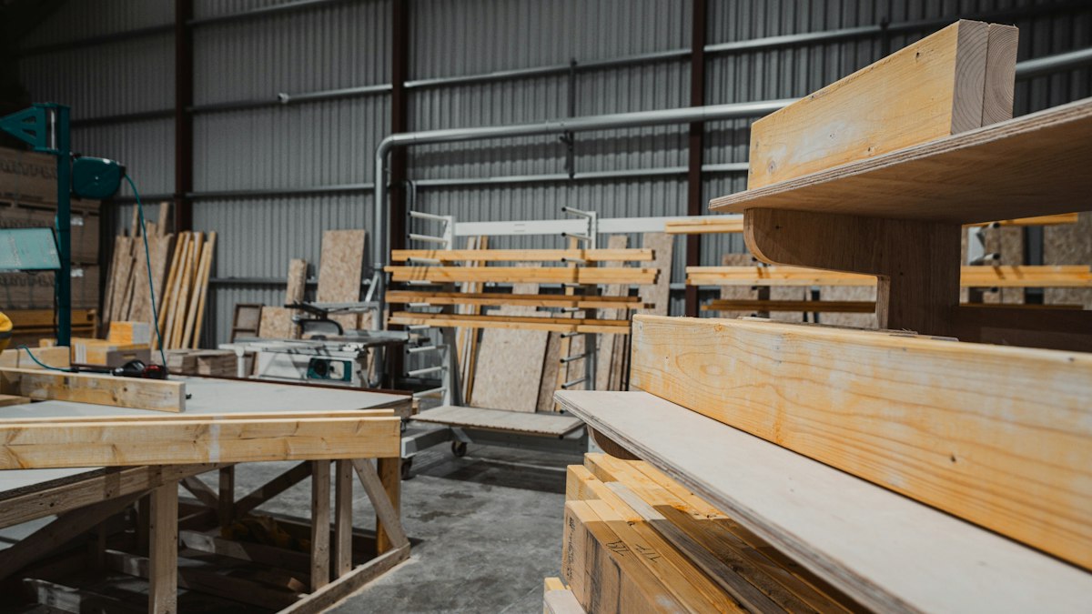 Tableros y listones de madera apilados en una nave de carpintería.